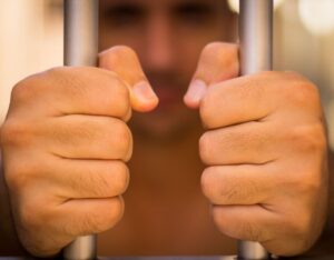 man behind jail bars holding them