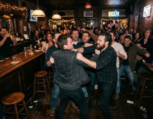 two men in a physical confrontation inside a crowded bar.